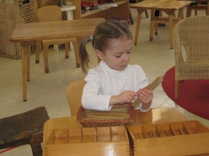M is working with the spindle boxes. This is a math material that helps the children see in a concrete way the value of zero as a place holder.